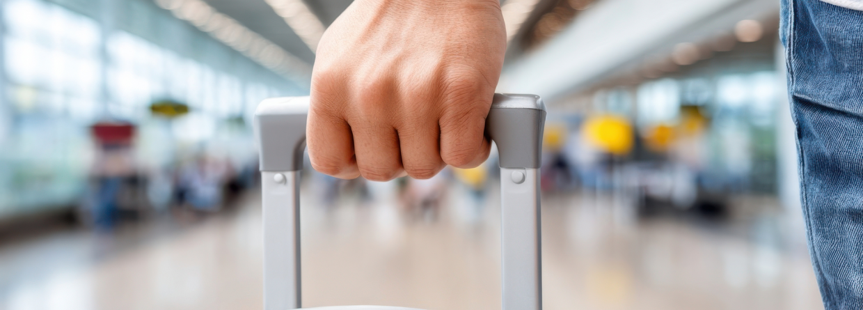 Persoon houdt koffer in zijn hand op een luchthaven