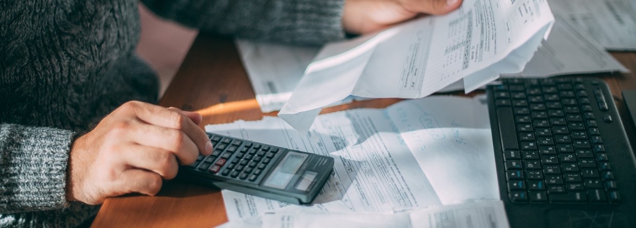 Een man achter een bureau met facturen op zijn bureau 