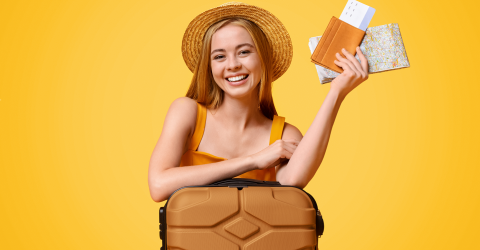 Vrolijke vrouwelijke toerist met een hoed op die leunt op haar koffer met haar paspoort, ticket en routekaart in haar hand